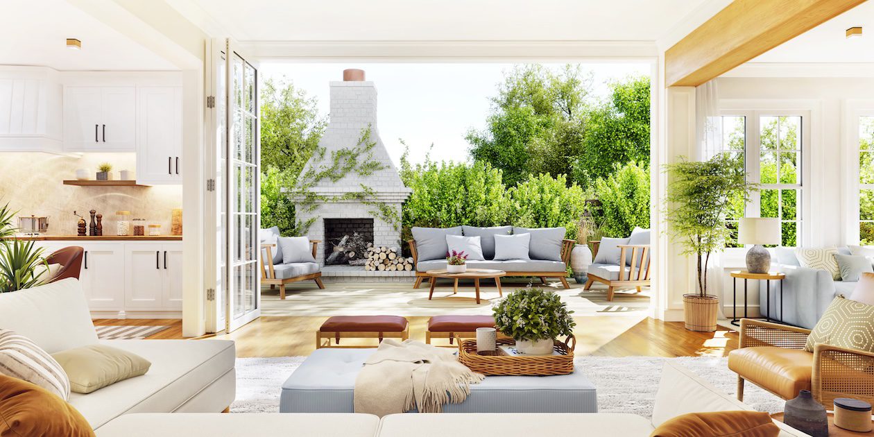 Open-plan living room and white kitchen flowing into a cozy outdoor patio with fireplace