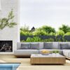 Outdoor patio with cushioned lounge furniture beside a swimming pool and modern outdoor fireplace, designed for sun exposure and coastal outdoor living.