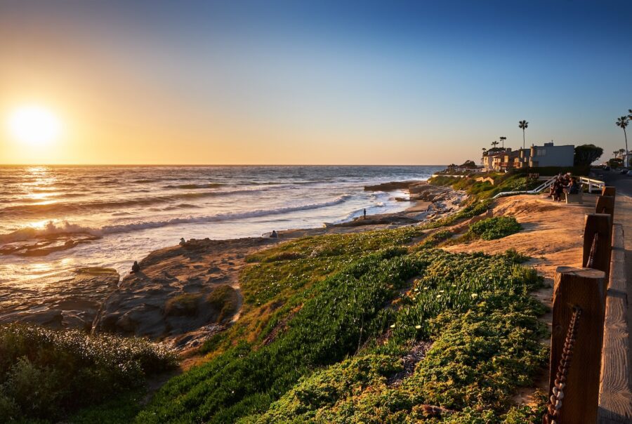 Sun setting over the northern end of Windansea Beach in San Diego, California, with golden light reflecting on ocean waves and rocky shoreline.