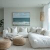 Modern coastal living room with white sectional, natural textures, and floor-to-ceiling windows overlooking the ocean