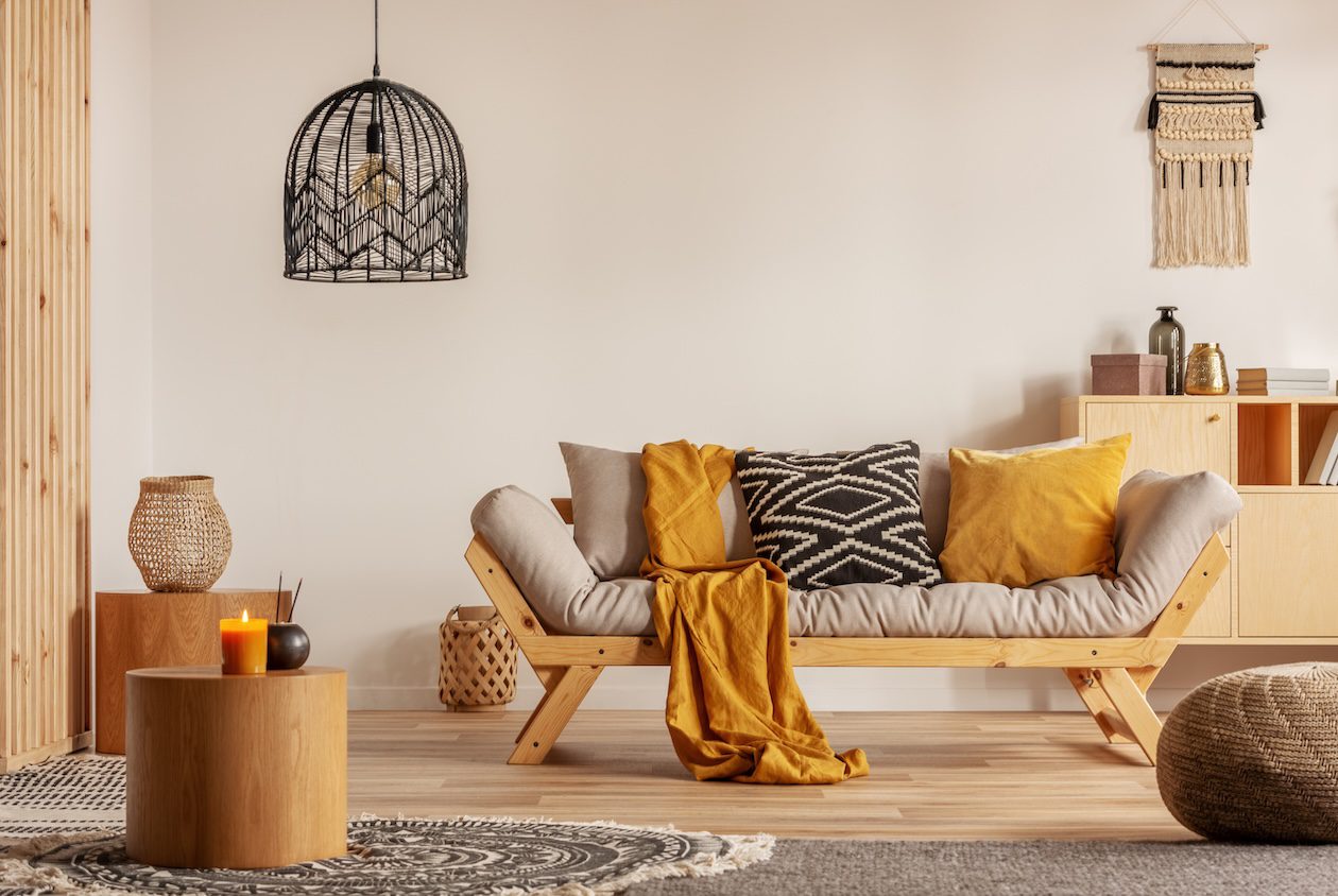 Scandinavian-style living room with sofa, layered pillows, and textured throw blanket demonstrating fabric scale and contrast in a bright interior
