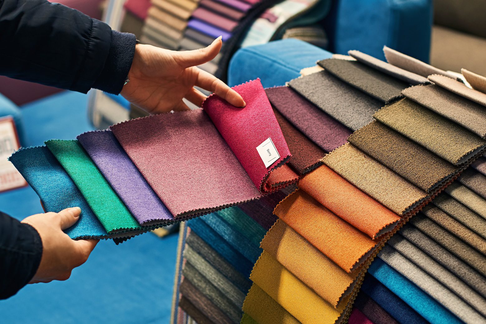Designer consulting with clients while reviewing upholstery fabric samples for custom upholstery, furniture selection, and indoor-outdoor living spaces.