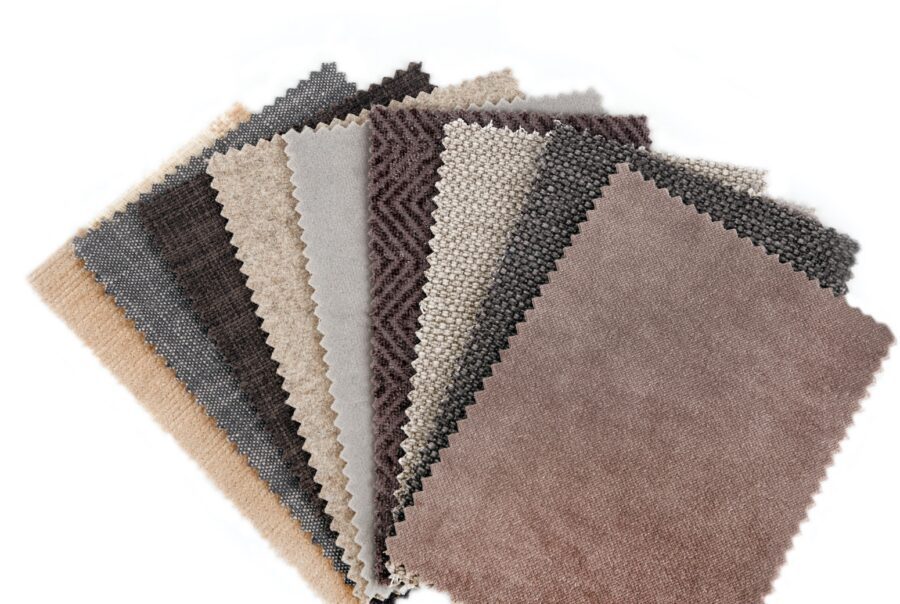 Collection of neutral-toned upholstery fabric swatches displaying various textures, weaves, and performance fabric finishes in shades of beige, gray, taupe, and brown.