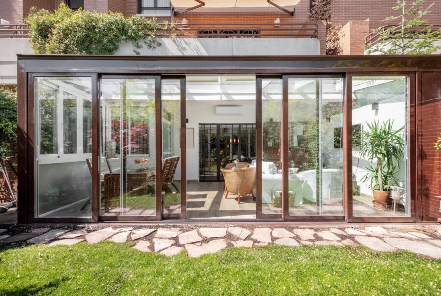 Contemporary home with expansive sliding glass doors creating a seamless indoor-outdoor living space, connecting a bright living room and dining area to a private patio and garden.