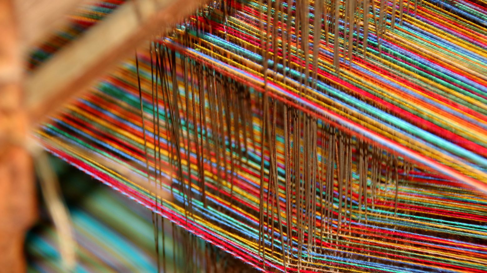 Close-up of a woven upholstery fabric being created on a textile loom, highlighting the intricate weave pattern, texture, and craftsmanship behind high-quality performance fabrics.