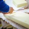 Close-up of a furniture maker shaping upholstery foam for a custom furniture piece in a professional workshop.