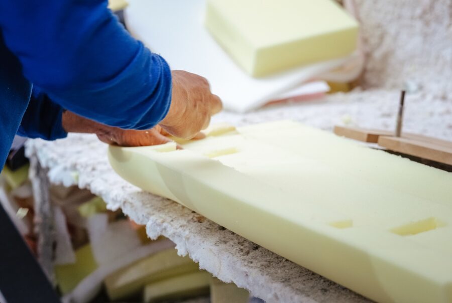 Close-up of a furniture maker shaping upholstery foam for a custom furniture piece in a professional workshop.