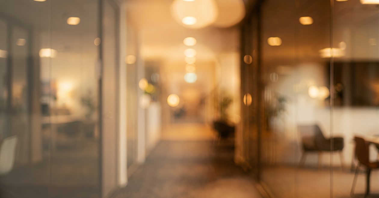 Softly blurred modern interior corridor with warm lighting, contemporary décor, and indoor plants creating a calm atmosphere.