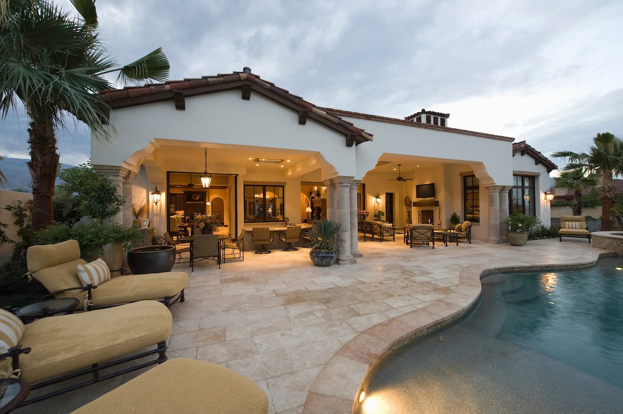 Luxury Southern California backyard with a covered patio, custom outdoor cushions, poolside lounge chairs, and seamless indoor-outdoor living.