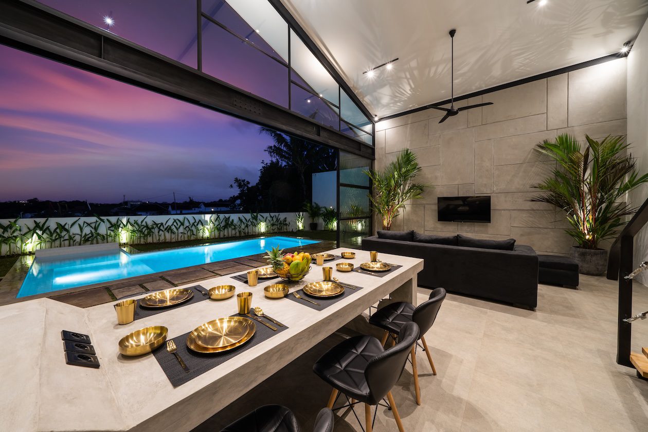 Open-concept living room overlooking a swimming pool and garden, highlighting seamless indoor-outdoor living.